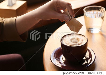 Woman adding sugar to aromatic coffee at table in cafe, closeup Woman adding sugar to aromatic coffee at table in cafe, closeup 102054493