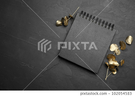Stylish black notebook and golden branches on table, flat lay. Space for text Stylish black notebook and golden branches on table, flat lay. Space for text 102054583
