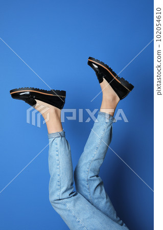 Woman wearing stylish shoes on blue background, closeup Woman wearing stylish shoes on blue background, closeup 102054610