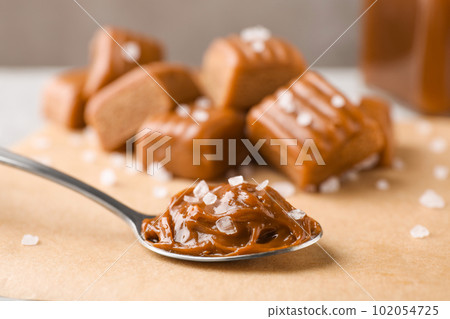 Salted caramel in spoon on parchment, closeup 102054725