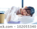 A young female worker who takes a nap and refreshes by the window in the office overlooking greenery 102055340