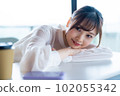 A young female worker who takes a nap and refreshes by the window in the office overlooking greenery 102055342