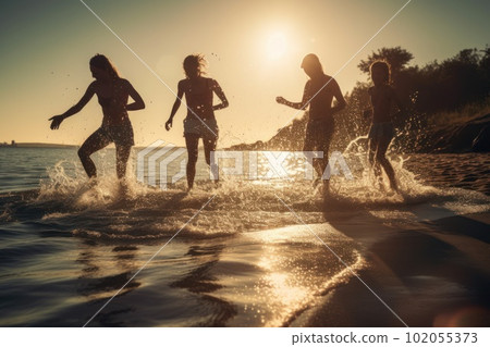 Backlit shot of teenagers running, having fun, playing and splashing water around them. At the beach during a sunny afternoon during summer break. Generative AI 102055373