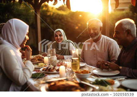 A family sitting together for iftar the breaking of fast at sunset.On the table full of traditional Ramadan foods. The family smiling and laughing. Generative AI A family sitting together for iftar the breaking of fast at sunset.On the table full of traditional Ramadan foods. The family smiling and laughing. Generative AI 102058539