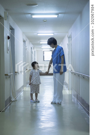 Nurse holding hands with girl patient in hospital corridor 102067984