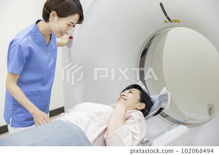 Radiologist woman encouraging middle-aged women undergoing CT examination 102068494