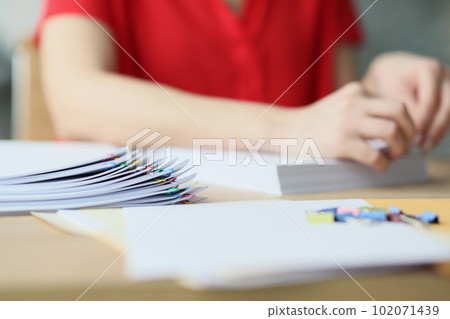 Secretary in red blouse fastens papers with pins in office 102071439