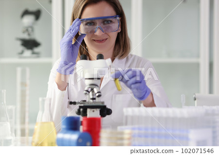 Positive woman adjusts goggles before examining sample 102071546