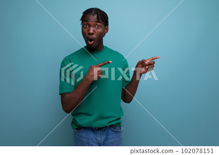 dark-skinned young man in a tank top pointing with a finger for the presence of an offer on an 102078151
