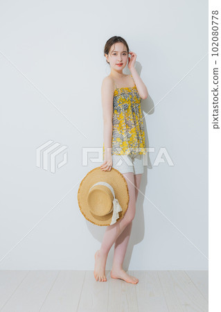 A woman holding a straw hat 102080778