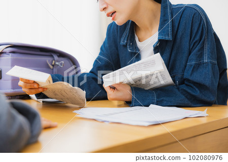 An elementary school student and her mother reading a letter in the living room 102080976