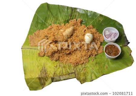 Hot chicken biryani with egg, raita and onion in banana leaf. A popular spicy non-vegetarian dish of India. top view Hot chicken biryani with egg, raita and onion in banana leaf. A popular spicy non-vegetarian dish of India. top view 102081711