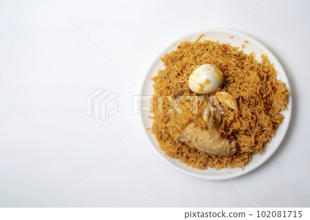 Top view of delicious spicy chicken biryani with egg on white plate, Ramadan festive food. Top view of delicious spicy chicken biryani with egg on white plate, Ramadan festive food. 102081715