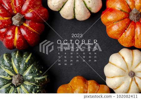The October 2023 Calendar and pumpkins on black cardboard background. 102082411