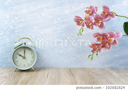 The Vintage alarm clock on wood floor and pink color orchid decorate, empty room for background. The Vintage alarm clock on wood floor and pink color orchid decorate, empty room for background. 102082824