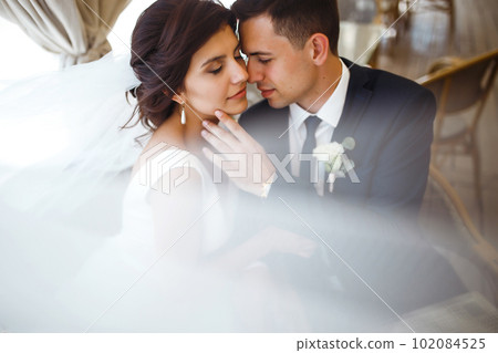 Young bride and groom in a cafe. Husband and wife hold each other's hands. Loving couple in a restaurant. Young bride and groom in a cafe. Husband and wife hold each other's hands. Loving couple in a restaurant. 102084525