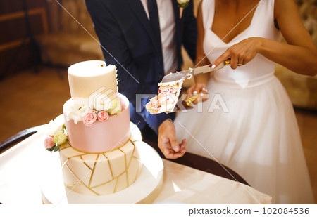 Happy bride and a groom is cutting their stylish wedding cake on wedding banquet. Sweet cake for couple. Happy bride and a groom is cutting their stylish wedding cake on wedding banquet. Sweet cake for couple. 102084536