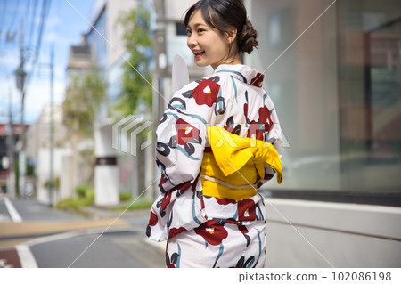 Back view of a young woman walking in the city in a yukata Back view of a young woman walking in the city in a yukata 102086198