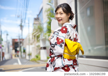 Back view of a young woman walking in the city in a yukata Back view of a young woman walking in the city in a yukata 102086199