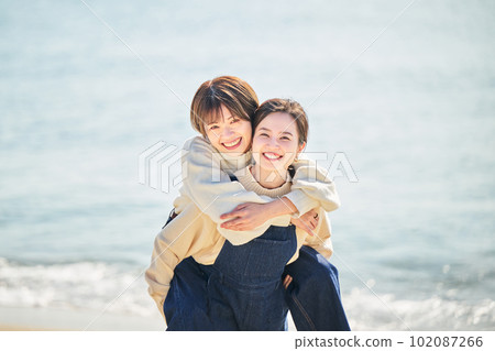 一個好年輕女人和她的朋友在海灘上背著她的朋友 一個好年輕女人和她的朋友在海灘上背著她的朋友 102087266