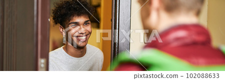 Its pizza time. Young guy looking happy while meeting courier with pizza box, spending time at home alone 102088633