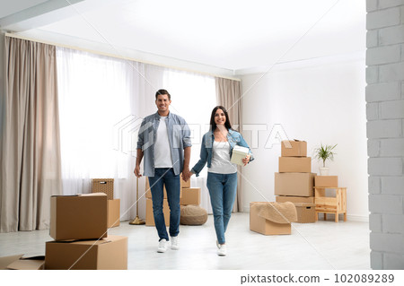 Happy couple in room with cardboard boxes on moving day Happy couple in room with cardboard boxes on moving day 102089289