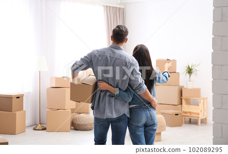 Couple in room with cardboard boxes on moving day 102089295