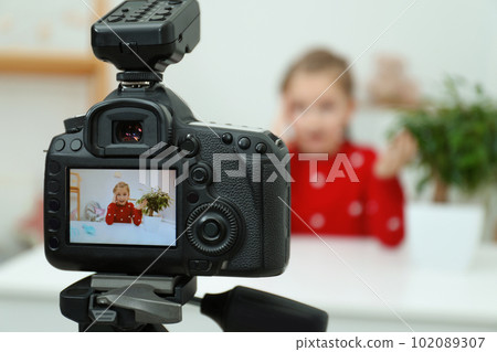 Cute little blogger with plant recording video at home, focus on camera Cute little blogger with plant recording video at home, focus on camera 102089307