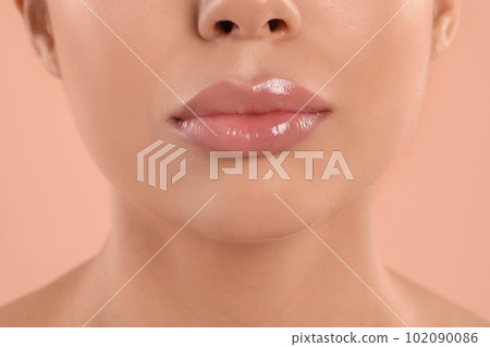 Young woman with beautiful full lips on peach background, closeup Young woman with beautiful full lips on peach background, closeup 102090086