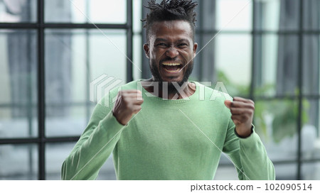 Winning ecstatic young African man clenching his fists with excited face 102090514