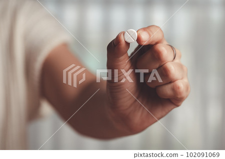 Asian woman's hand holding a white pill for medical and healthcare concept. Asian woman's hand holding a white pill for medical and healthcare concept. 102091069