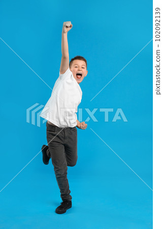 Full length portrait of emotional preteen boy on blue background 102092139