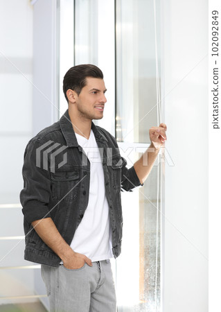 Handsome man wearing casual outfit near window at home Handsome man wearing casual outfit near window at home 102092849