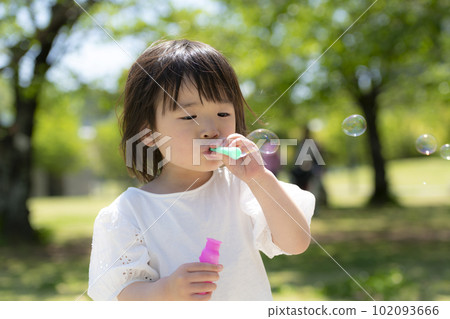 A little girl playing with soap bubbles in a fresh green early summer park A little girl playing with soap bubbles in a fresh green early summer park 102093666