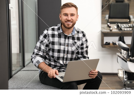 Young business owner with laptop in his barber shop 102093909