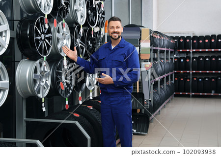 Male mechanic near car tires and alloy wheels in auto store 102093938