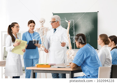 Medical students and professor studying human spine structure in classroom 102094228