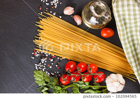 Pasta and cooking ingredients on black slate background. 102094565