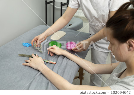 Female, Teenager with Disability Stretches Fingers With Physical Therapy Equipment. Health Specialist, Rehabilitation Of Cerebral Palsy, Athetosis. Horizontal plane Female, Teenager with Disability Stretches Fingers With Physical Therapy Equipment. Health Specialist, Rehabilitation Of Cerebral Palsy, Athetosis. Horizontal plane 102094642
