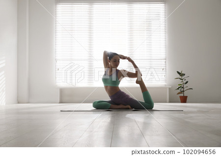 Woman practicing one legged king pigeon asana in yoga studio. Eka pada rajakapotasana 102094656