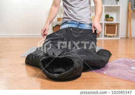 A man folds winter jackets and puts them in a 102095347