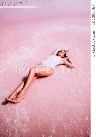 Woman in a pink salt lake. She lies in a white bathing suit. Wanderlust photo for memory 102096467