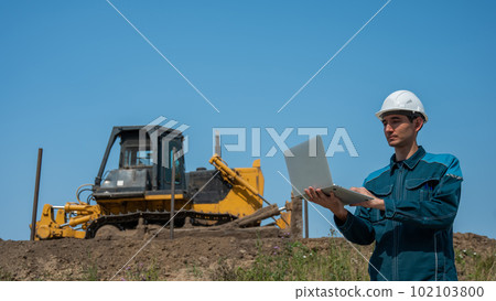 Caucasian male builder in hardhat holding laptop at construction site. Caucasian male builder in hardhat holding laptop at construction site. 102103800