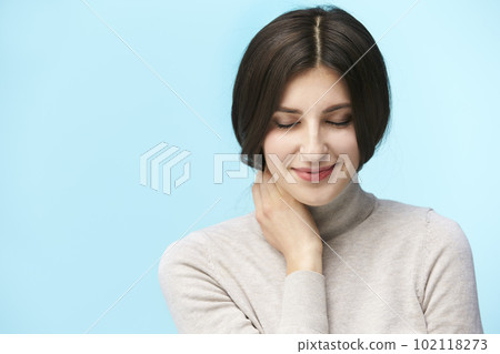 portrait of a beautiful young caucasian woman, happy and smiling, eyes closed, isolated on blue background 102118273