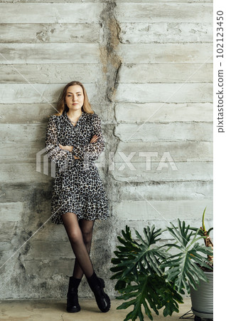 Beautiful blonde girl in a gray dress and black shoes posing against the wall Beautiful blonde girl in a gray dress and black shoes posing against the wall 102123450
