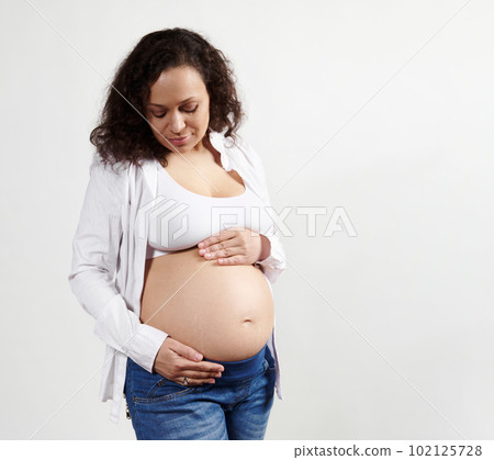 Middle aged curly haired beautiful brunette pregnant woman expecting baby, holding and caressing her naked belly, enjoying her caferee happy pregnancy, isolated on white background. 9 month. Maternity Middle aged curly haired beautiful brunette pregnant woman expecting baby, holding and caressing her naked belly, enjoying her caferee happy pregnancy, isolated on white background. 9 month. Maternity 102125728