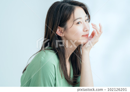 在陽光透過樹葉的白色背景下做護膚的年輕女性 102126201