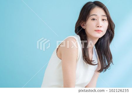 A young woman doing skin care on a blue background where the sun shines 102126235