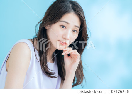 A young woman doing skin care on a blue background where the sun shines 102126236