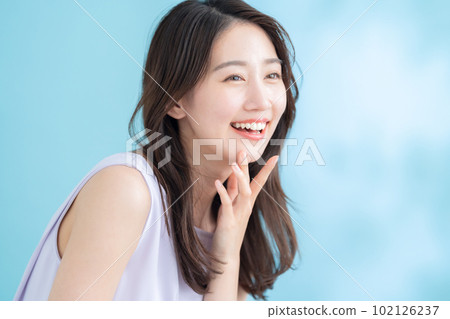 A young woman doing skin care on a blue background where the sun shines A young woman doing skin care on a blue background where the sun shines 102126237